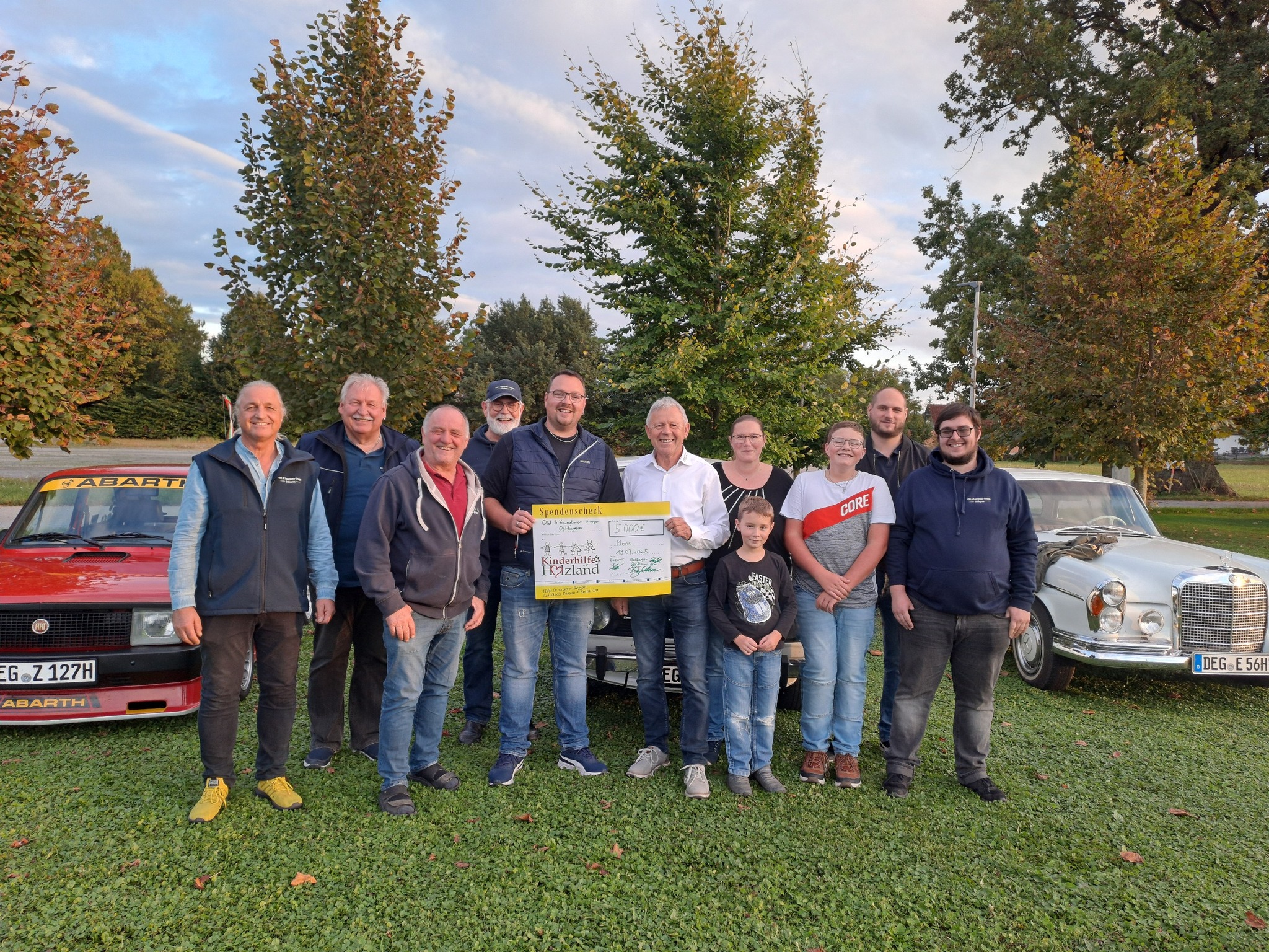 Gemeinsam für den guten Zweck ist seit Jahren das Motto der Oldtimerfreunde aus Moos. Auch dieses Jahr konnte bei der traditionellen Benefizrallye wieder eine ordentliche Spendensumme gesammelt werden. Zusätzlich zu den 125 Oldtimern die an den Start gingen, fanden sich nochmal etwa 800 Klassiker auf dem parallel stattfindenden Oldtimertreffen ein.  Die Spenden der Fahrer und Besucher füllten rasch die Spendenkasse. Auch weitere Mooser Vereine beteiligten sich an der Spendenaktion. Vor kurzem wurden nun die gesammelten Spenden an Peter Stuiber, den ersten Vorsitzenden der Kinderhilfe Holzland e.V übergeben. Dieser nahm dankbar den Scheck über 5000€ entgegen und freute sich, dass die Kinderhilfe damit Kindern in Not sowie deren Familien helfen kann. Auch nächstes Jahr findet die Oldtimerrallye für den guten Zweck wieder in Moos statt. Der Termin ist der 11.07.2026.
